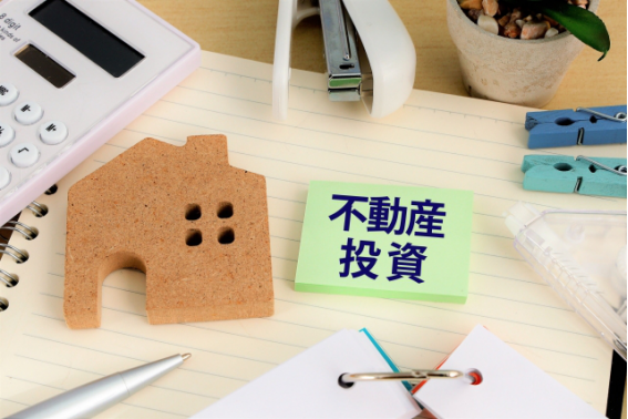 不動産投資ローンとマンション購入を検討するイメージ(家の模型と契約書の写真)