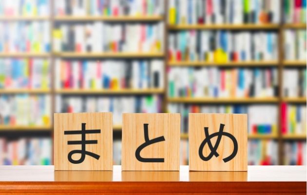 本棚の背景がぼやかされており、手前の棚に木のブロックで「まとめ」と書いてある写真