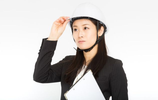 女性がヘルメットを被り、ヘルメットを触っている。女性の防災管理者の写真。