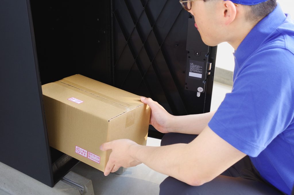 宅配ボックスに荷物を入れる男性