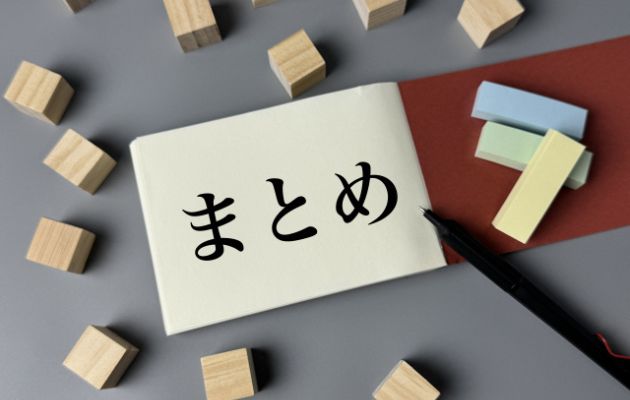 ノートに「まとめ」と書いてあり、周りに気のブロックと付箋、ボールペンが置いてある写真
