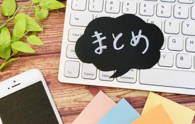 キーボードの上に黒の吹き出しで「まとめ」と書かれている写真。周りにはスマートフォンと付箋が置いてある。