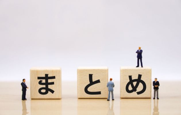 積み木に「まとめ」と書かれている写真。積み木の周りにビジネスマンに人形が立っている。
