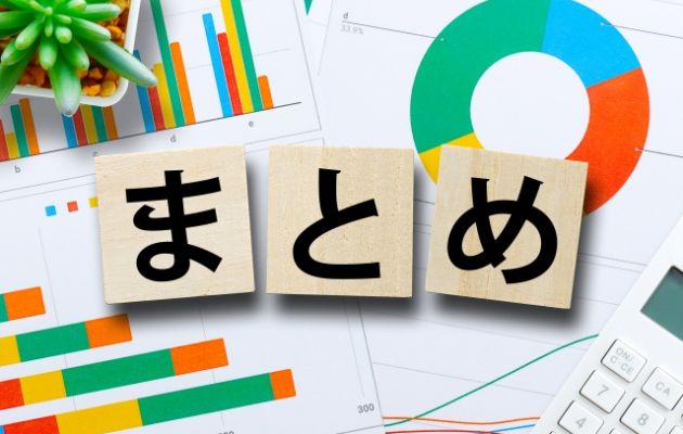 棒グラフや円グラフの資料の上に木のブロックに「まとめ」と書いてある写真