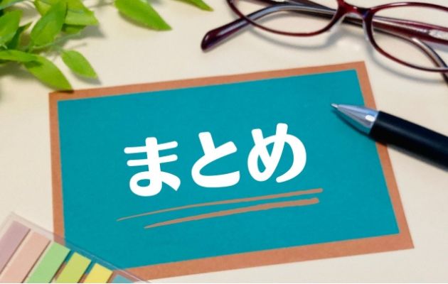 緑の用紙に白文字で「まとめ」と書かれており、周りにメガネと付箋、ボールペンが置いてある写真