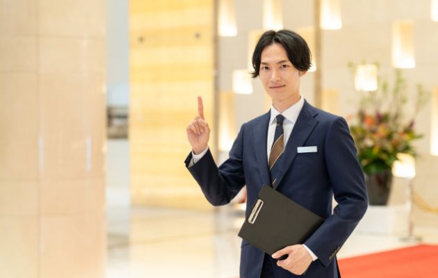男性コンシェルジュが人っし指を出して、内容を説明しようとしている写真