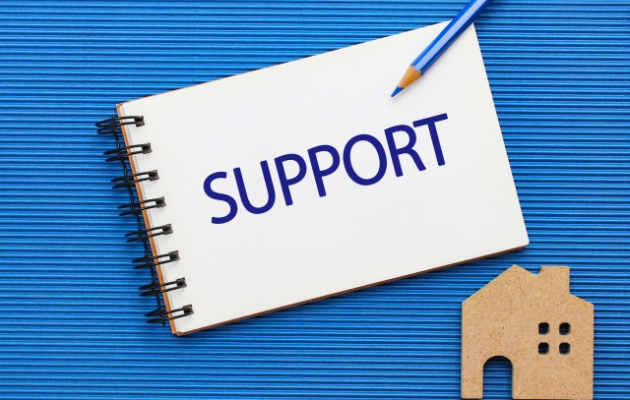 ノートに「SUPPORT」と書かれていて、ノートの下にコルクの家が置いてある写真