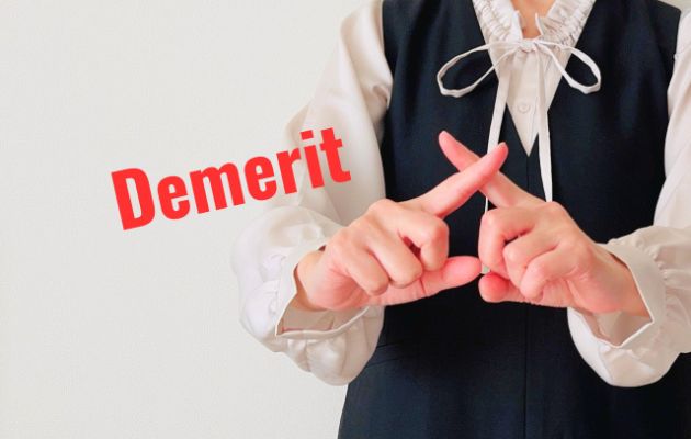 女性が胸の前で指を交差させてバツを表している。その横に赤字で「Demerit」と書かれている写真