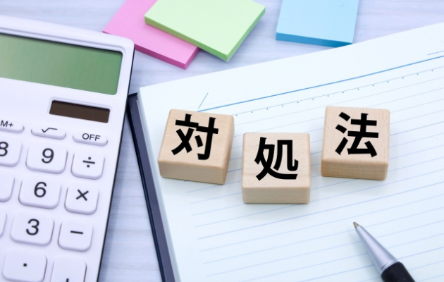 ノートの上に積み木で「対処法」と書いてある。周りに電卓と付箋が置いてある写真