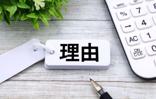 暗記カードに「理由」と書かれており、周りに電卓とボールペンが置いてある写真