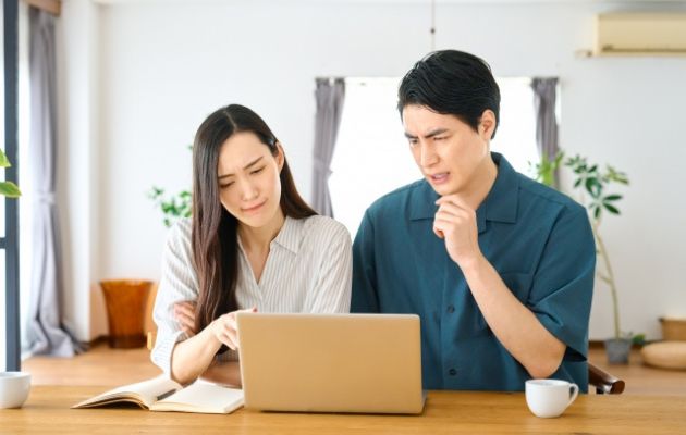 税金の計算方法をパソコンで調べながら悩んでいる男女の写真