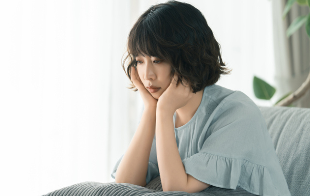 女性が頬に手を添えて、引き受けたくない時の選択肢を考えている写真