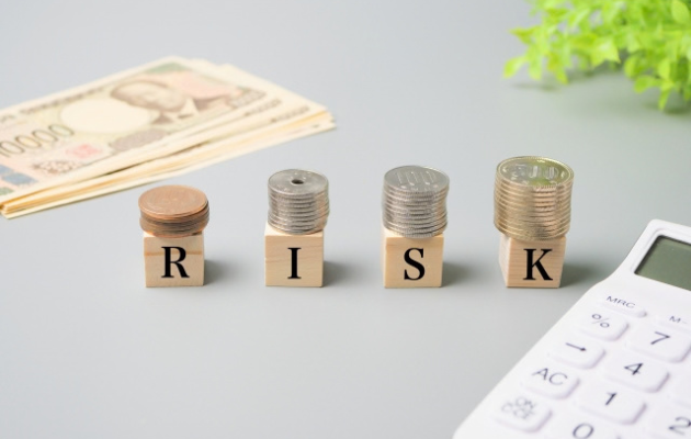積み木に「RISK」と書かれており、その上に硬貨が積まれている写真
