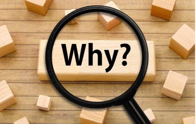 積み木に「Why?」と書かれており、上から虫眼鏡で文字を写している写真