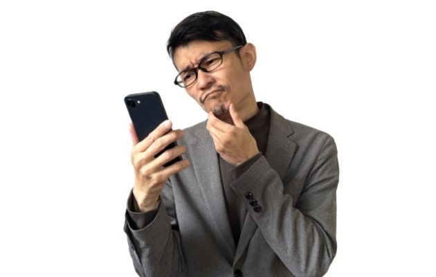 スマホを見て、嘘なのか考えている男性の写真